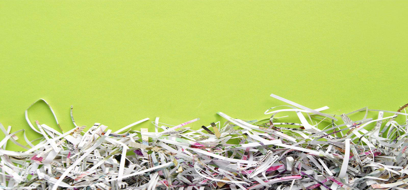 Image shows paper shredded documents piled against a green background.