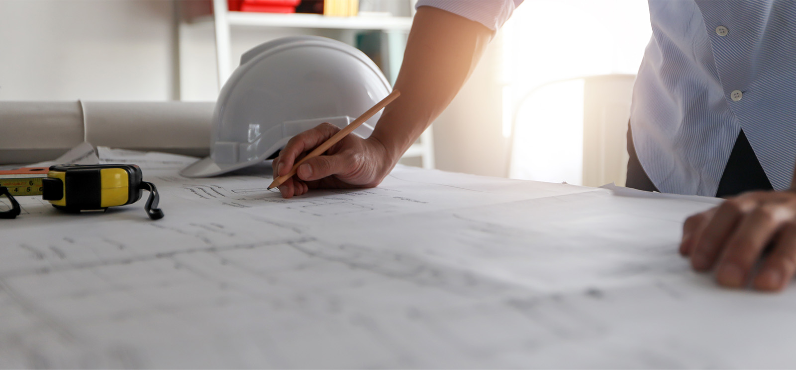 Close up hand of engineer drawing and drafting on blueprint on table.
