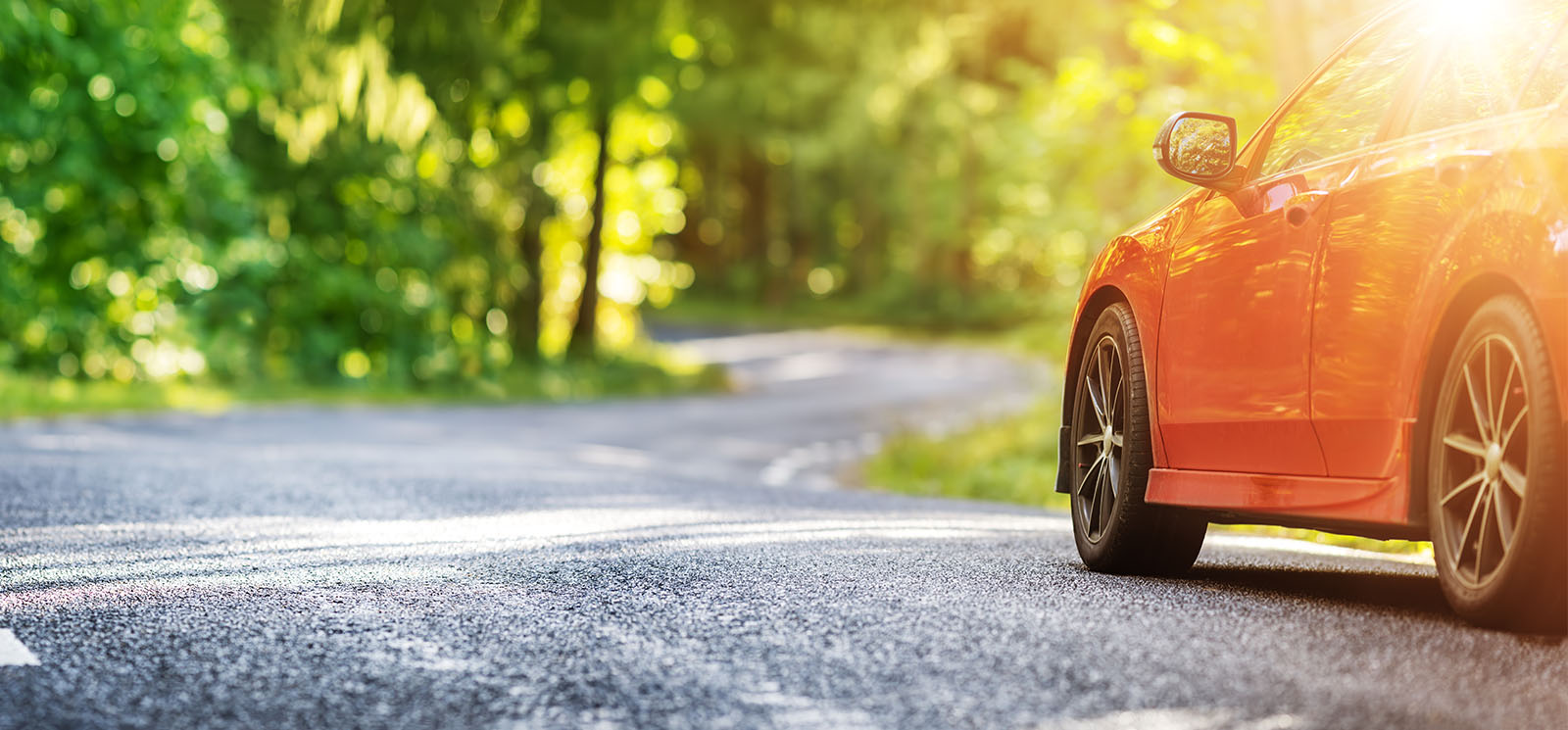 red car on asphalt road in summer