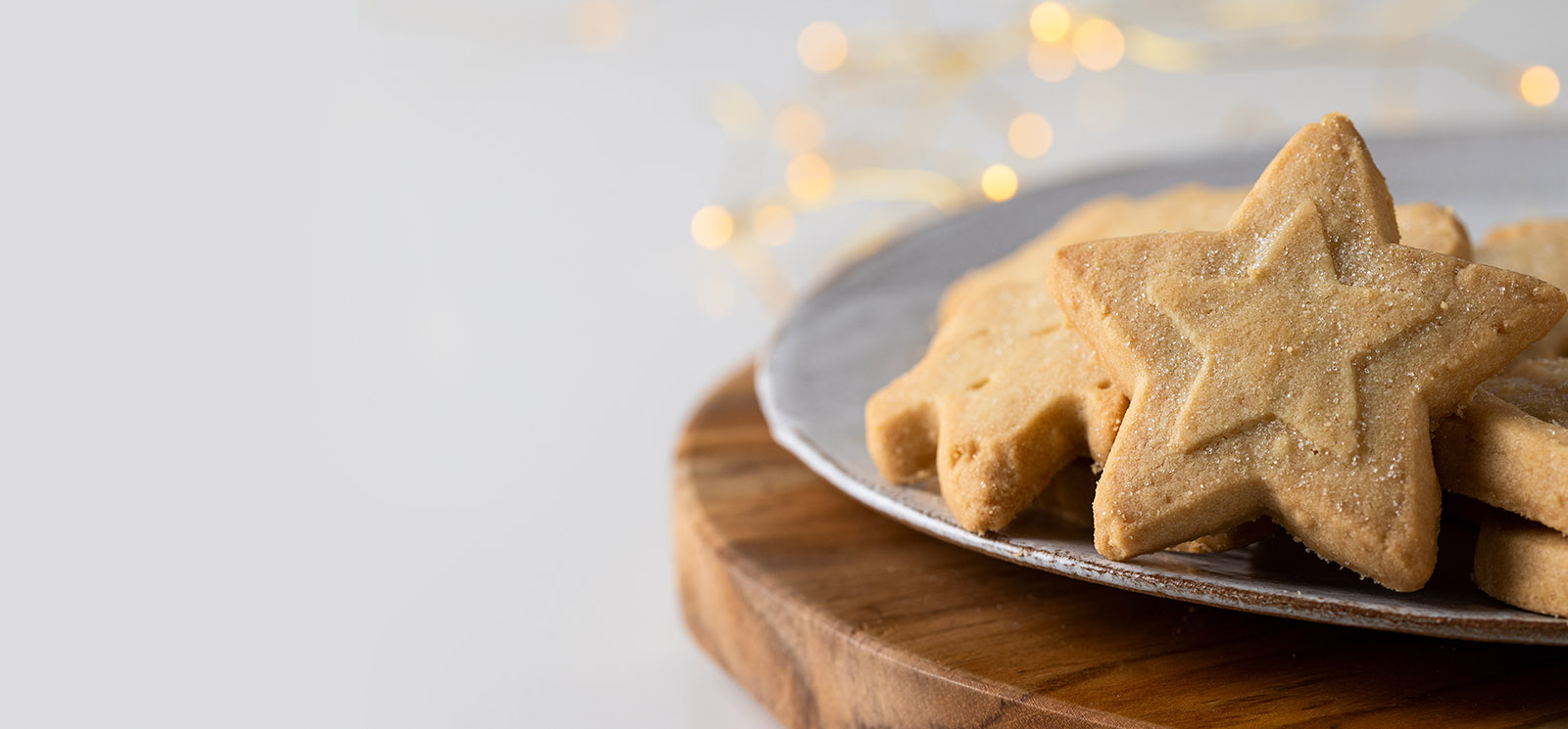 Shortbread Christmas cookies, different festive shape on the white plate with bokeh.