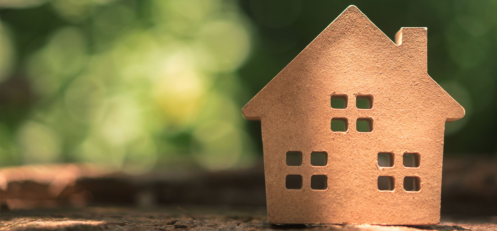 Small home model on wooden table with nature green bokeh abstract background.