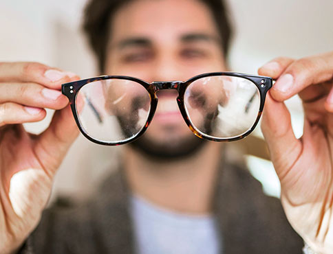 Man holding up and looking through glasses.