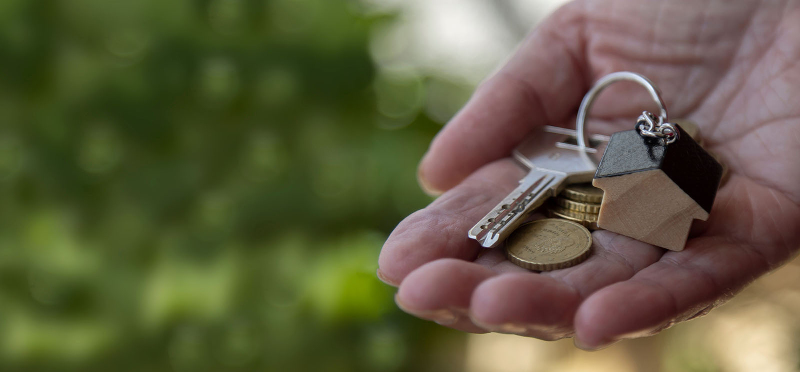 woman holding keys and money with little house keychain