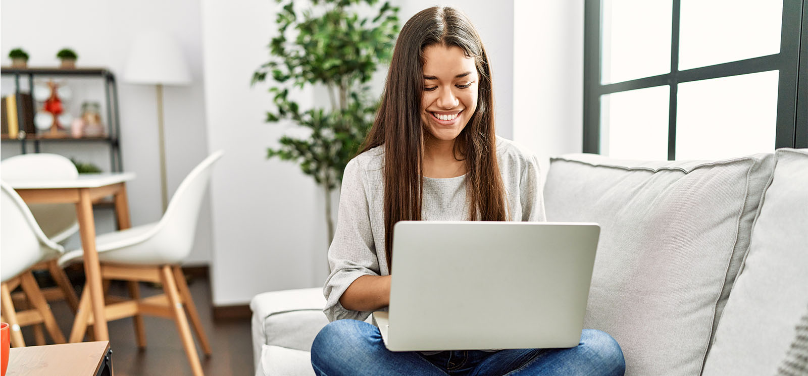 Young latin woman using laptop sitting on sofa at home