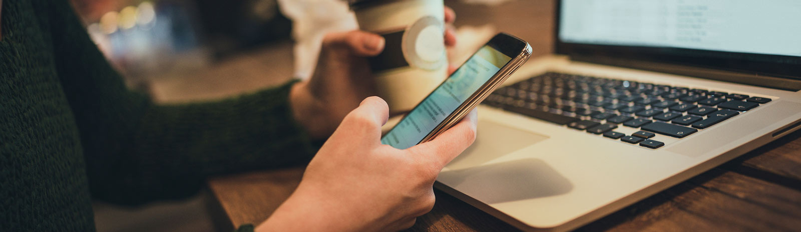 Close up of phone and laptop at coffee shop.